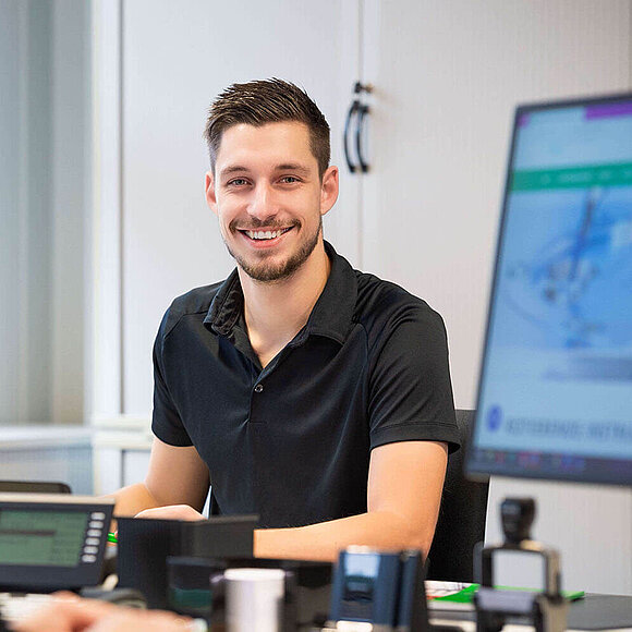 Junger Vertriebsmitarbeiter lächelt in die Kamera